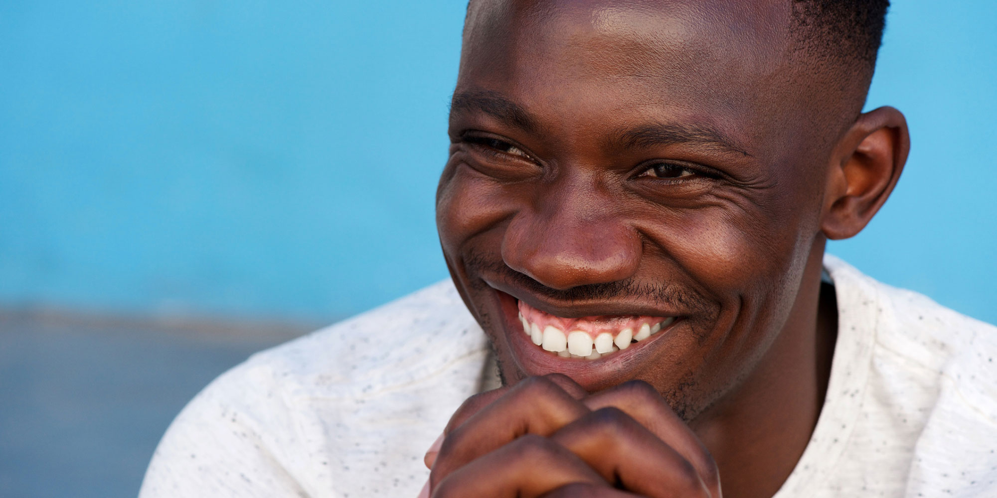 Man smiling and prying outside
